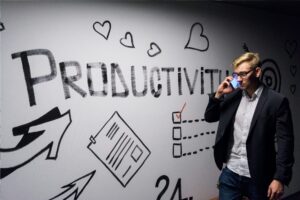 Man in a blazer talks on a cellphone beside a productivity-themed wall mural with hearts and checkboxes in the background.