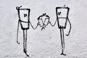 Two stick figures connected by a string telephone using cups between them.