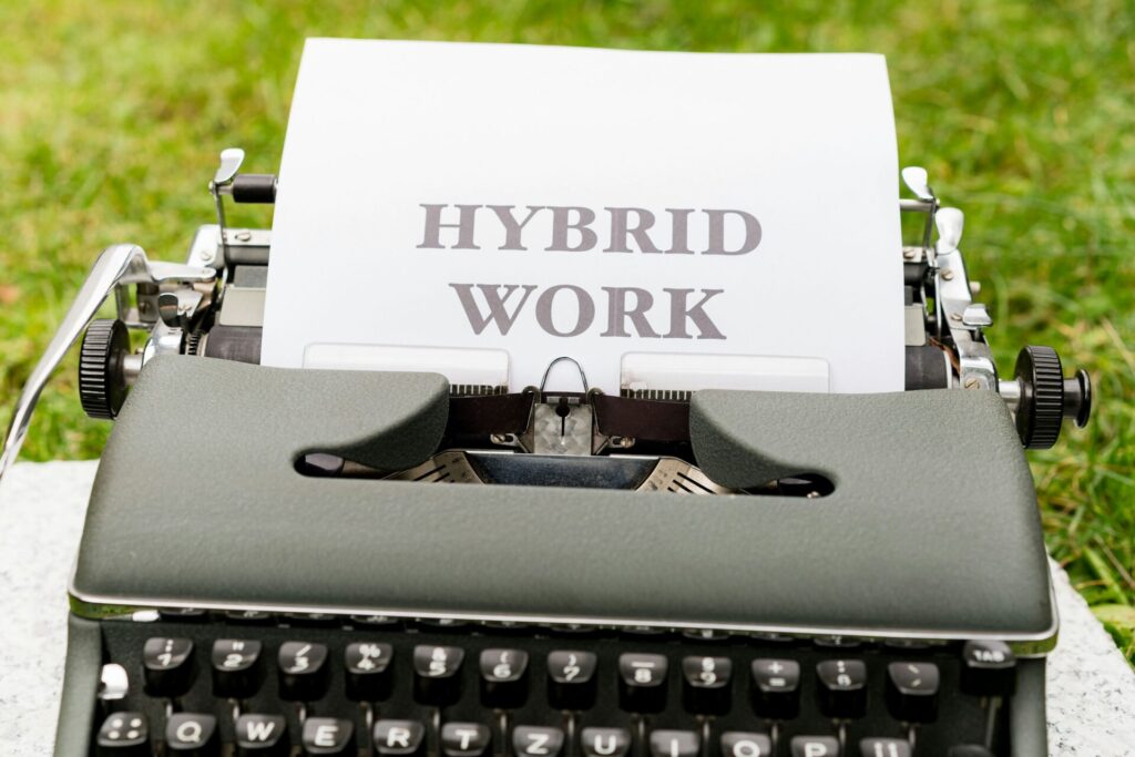 Vintage typewriter on grass with a sheet reading 'HYBRID WORK'