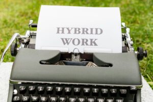 Vintage typewriter on grass with a sheet reading 'HYBRID WORK'