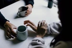 Hands reaching for gray mugs on a white table during a casual meetup.